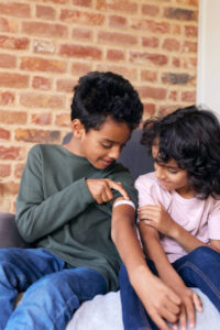 Boy showing younger brother plaster on arm
